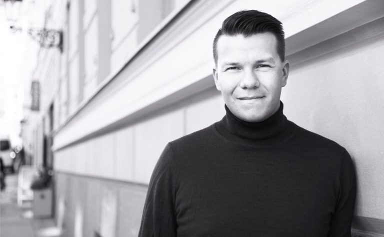 Mustavalkoinen kuva, Mikkel katsoo kameraan.